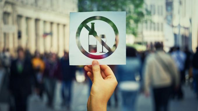 Main tenant une feuille de papier sans signe d'alcool sur un fond de rue bondée. Arrêter de boire l'icône interdite de symbole. Refusez d'être dépendant.