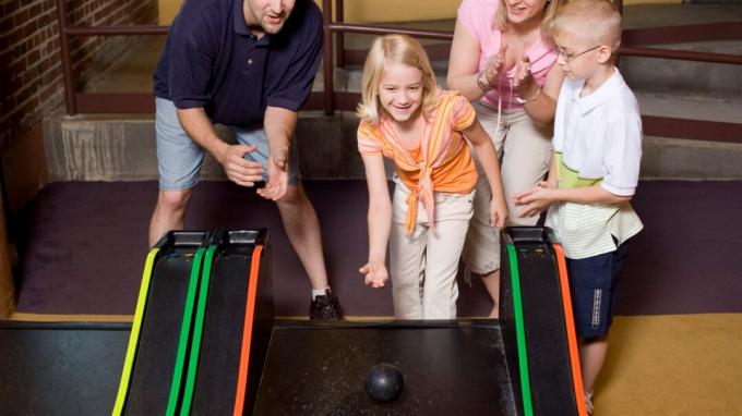 Une famille heureuse qui passe du temps ensemble et joue à des jeux dans une salle d'arcade, grâce à une parentalité positive