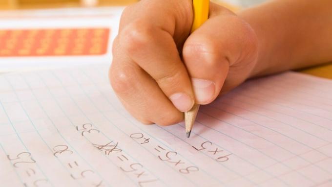 La main d'un enfant accomplissant un devoir avec l'aide d'aménagements mathématiques